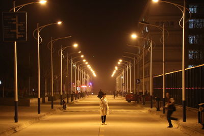People walking on illuminated street at night