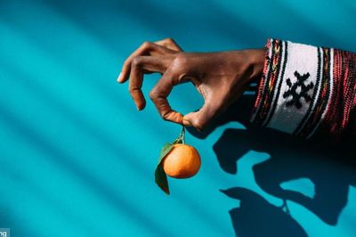 Close-up of hand holding apple against blue background