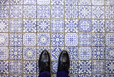 Low section of man standing on tiled floor