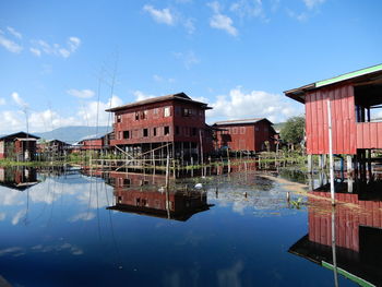 Reflection of stilt houses in lake  inle against sky in myanmar. 