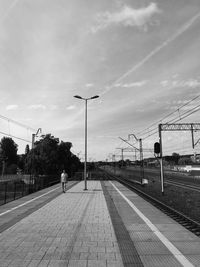 Man on railroad track in city against sky