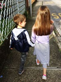 Rear view of siblings walking on footpath