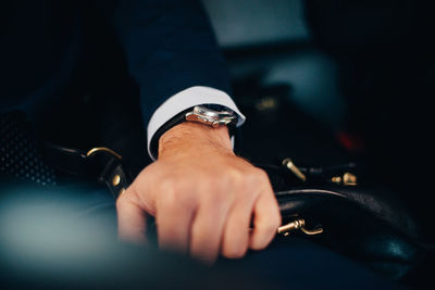 Cropped image of mature businessman holding bag on seat in taxi