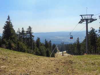 Overhead cable car on field against sky