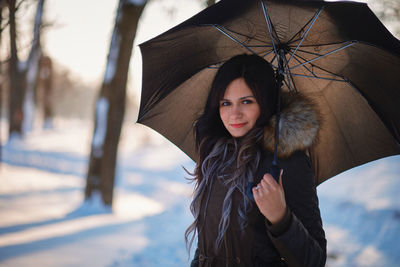 Portrait of woman holding umbrella while standing on outdoors during winter