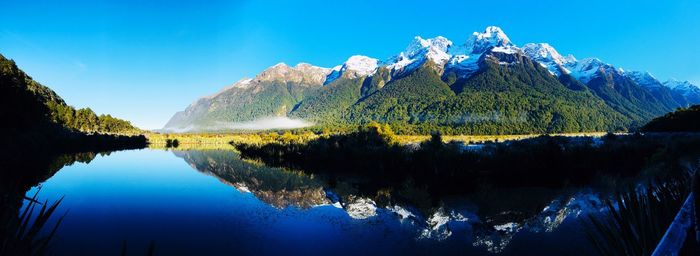 Scenic view of lake and mountains against blue sky