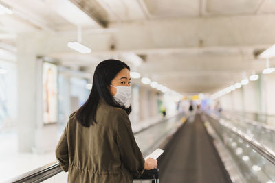 Woman looking through smart phone while standing on escalator