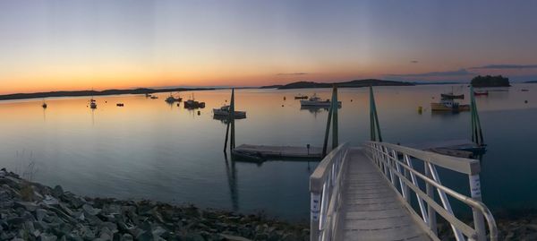 Sailboats moored in marina at sunset