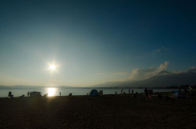 Silhouette people on beach against sky during sunset