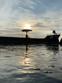 Silhouette boat in sea against sky during sunset