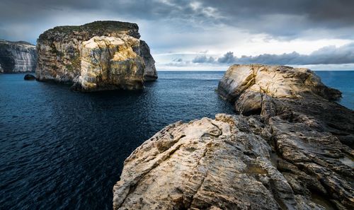 Rock formation on sea shore against sky