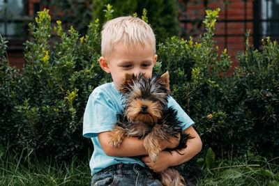 Boy with yorkshire terrier dog puppy. cute baby boy hugs york terrier puppy and siting on 