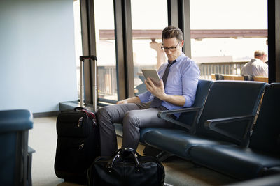 Businessman using tablet computer while sitting in waiting area at subway station