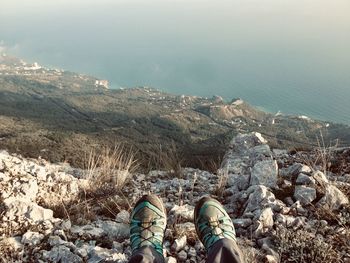 Low section of person on cliff against sea