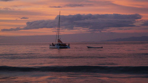 Sailboat sailing on sea against sky during sunset