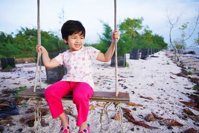 A girl is rocking in a tree on the beach