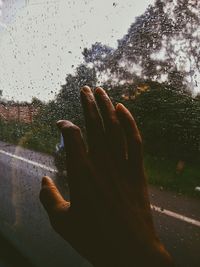 Cropped hand touching wet window while traveling in bus