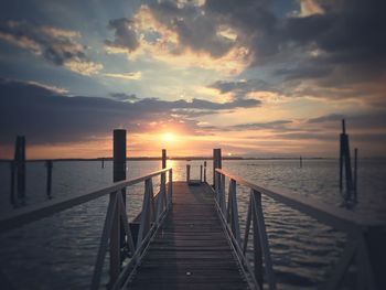 Pier over sea against sky during sunset