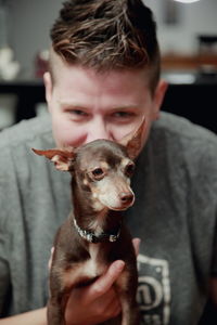 Portrait of happy woman holding miniature pinscher at home