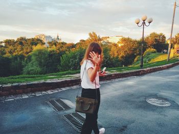 Young woman standing on road against sky