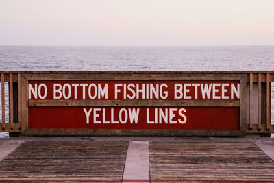 Information sign by sea against clear sky