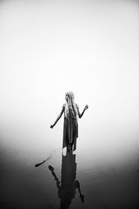 Rear view of woman standing in sea against clear sky