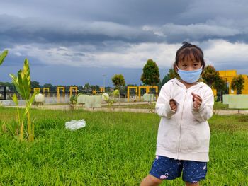 Portrait of boy standing on field against sky