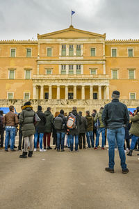 Rear view of people standing against buildings in city