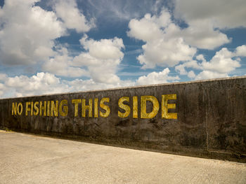 Colour image of a wall at brighton marina, with  'no fishing this side' painted in yellow capitals