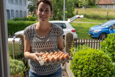 Portrait of smiling young woman selling eggs for small business