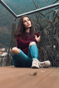Thoughtful young woman sitting against railing