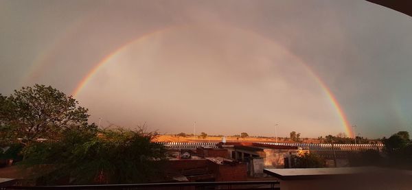 Rainbow over buildings in city against sky