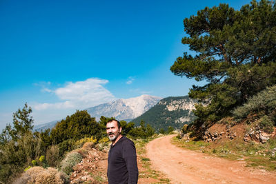 Portrait of young man standing on mountain against sky