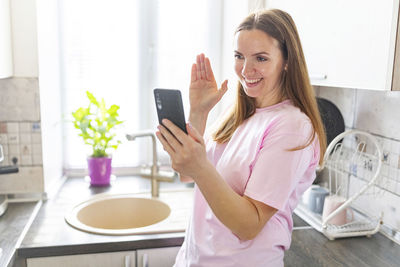 Portrait of young woman using mobile phone at home