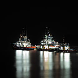 Boats in sea against sky at night