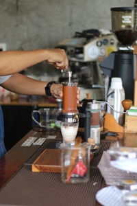 Midsection of woman pouring coffee in cafe