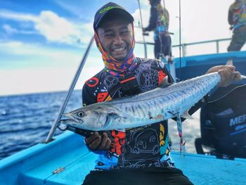 A happy man caught big spanish mackerel boating in sea