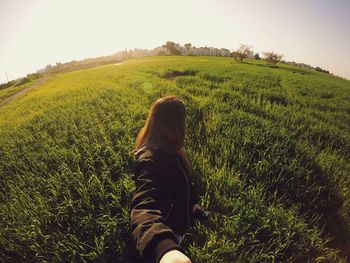 Woman standing on grassy on field against clear sky