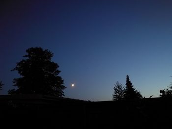 Low angle view of silhouette trees against clear blue sky