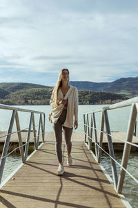 Smiling young woman looking away while walking on jetty