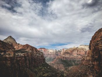 Rock formations on landscape against cloudy sky