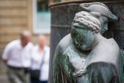 Close-up of weathered statues against people