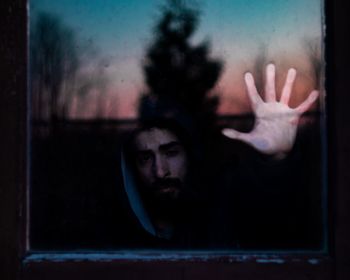 Portrait of young man against window