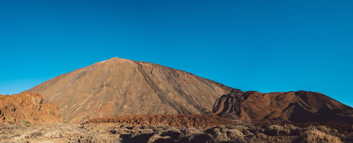 Scenic view of volcanic mountain against clear blue sky