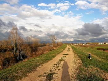 Road amidst field against sky