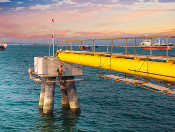 Workers are repairing and painting bollard for mooring on sea at industrial port