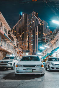 Traffic on road by buildings at night