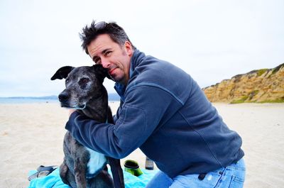 Man with dog at beach against sky