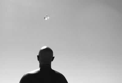 Rear view of bald man with crystal balls against clear sky