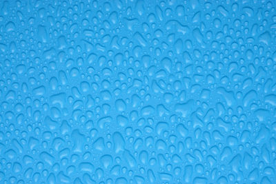 Full frame shot of water drops on blue surface